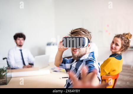 Young group of colleagues using VR technology in a startup company office. Virtual reality in business. Stock Photo