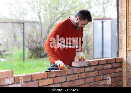 a man builds a wall of bricks, lays a brick on a cement sand mortar Stock Photo