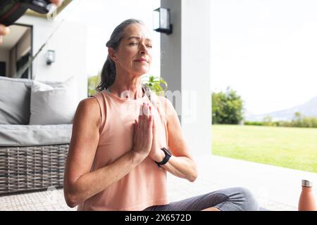 At home, Caucasian mature woman practicing yoga outside Stock Photo
