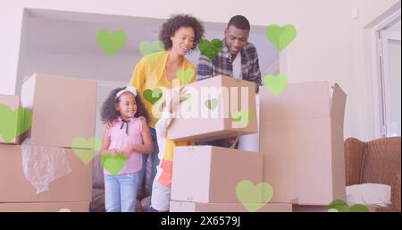 Diverse family unpacking boxes in new home, daughter holding one Stock Photo