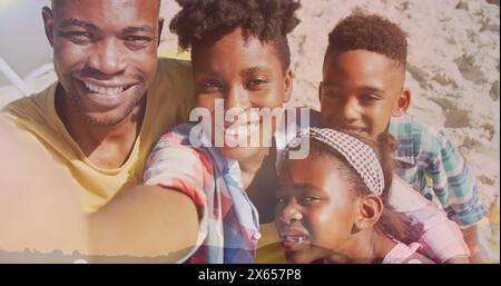 African American family enjoying time on beach, father holding camera Stock Photo