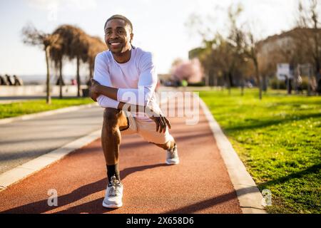 Young african-american man is exercising in the city. He is stretching his body. Stock Photo