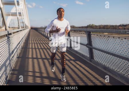 Young african-american man is jogging on the bridge in the city. Stock Photo