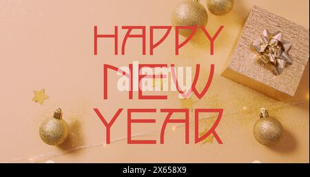 Golden baubles and stars are scattered around gift box on a glittery surface Stock Photo