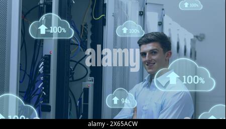 Image of clouds with increasing numbers over smiling caucasian man standing at servers Stock Photo