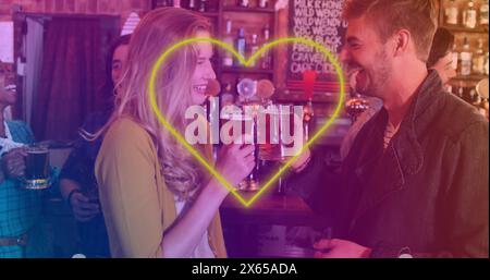 Image of neon yellow heart flickering over caucasian couple having beer in bar Stock Photo