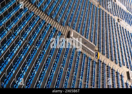 High-angle view of empty blue and gray stadium seats arranged in a repetitive pattern, capturing the quiet before an event. Stock Photo