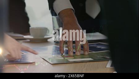 Multiple people standing around table, examining documents and charts Stock Photo