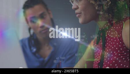 Biracial couple, both young, are looking at colorful data on screen Stock Photo
