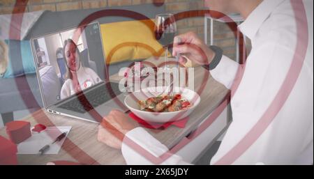 Middle-aged man dining, toasting wine to young girlfriend on laptop Stock Photo
