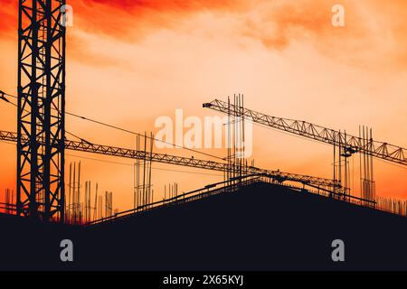 Construction site building scaffold and cranes in silhouette against dramatic orange sunset sky Stock Photo