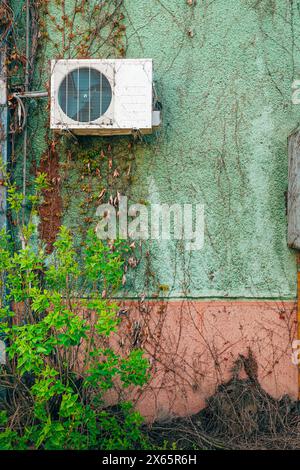 Old used air conditioning external device mounted on house exterior wall, copy sp[ace included Stock Photo