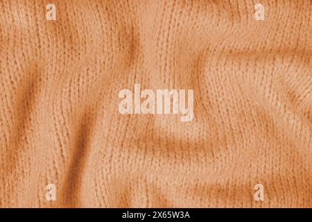 Close up background of orange knitted fabric made of viscose yarn. Crumpled knitting wool, soft knitwear texture background. Abstract knitted wrinkled Stock Photo