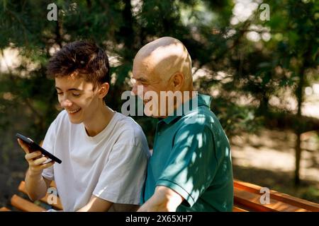 Portrait of senior man with his grandson using mobile Stock Photo