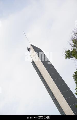 A tall minimalist tower with trees around it with a clear sky Stock Photo