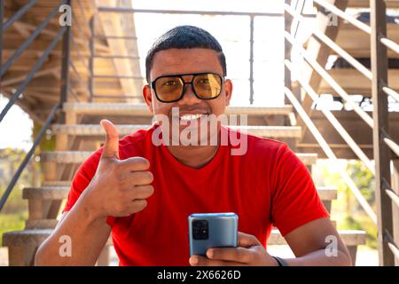 portrait smiling young black man pointing thumb up on blur background Stock Photo