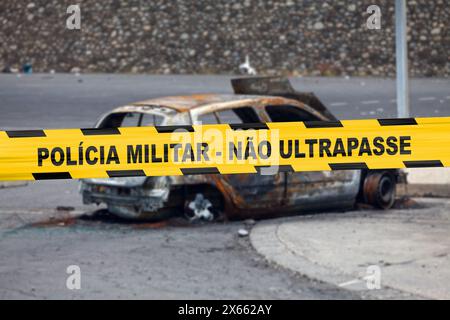 Car burnt by a pyromaniac with a police tape with written in it in Portuguese 'Polícia militar - Não ultrapasse'. Stock Photo