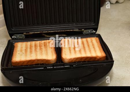 The picture shows an electric grill with toasted toast for making sandwiches. Stock Photo