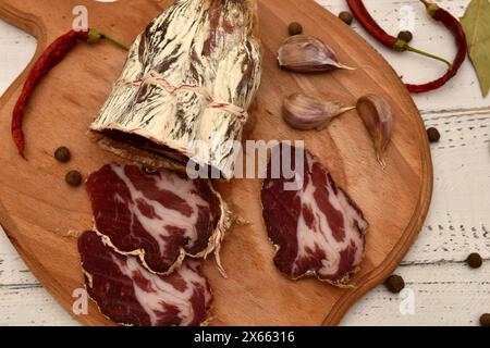 On a cutting board is the Italian cuisine coppa meat, which has been cut into slices. Stock Photo