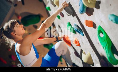 Athletic Female Rock Climber Practicing Solo Climbing on Bouldering Wall in Gym. Female Exercising at Indoor Fitness Facility, Doing Extreme Sport for Her Healthy Lifestyle Training. Close Up Portrait Stock Photo