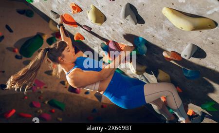 Athletic Female Rock Climber Practicing Solo Climbing on Bouldering Wall in Gym. Female Exercising at Indoor Fitness Facility, Doing Extreme Sport for Her Healthy Lifestyle Training. Close Up Portrait Stock Photo