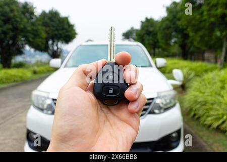 Car key in hand with car on the background. Car stuff concept. After some edits. Stock Photo