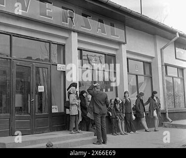Socialist Republic of Romania in the 1970s. People staying in line in front of a state-owned grocery store, waiting for the delivery of food. The centralized socialist economic system created scarcity and hunger. Stock Photo