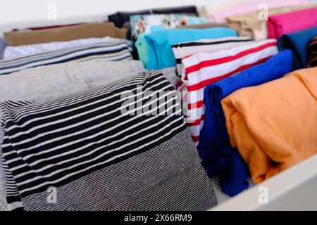 bunch of colorful clothes, woman is cleaning out her wardrobe, Vertical storage of clothing in white mesh metal basket, homemaking tips, tidying up, h Stock Photo
