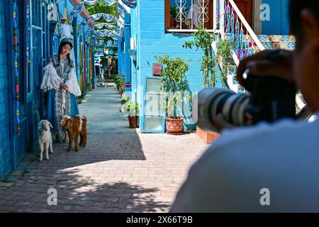 Yining, China's Xinjiang Uygur Autonomous Region. 10th May, 2024. A tourist poses for photos on the Liuxing Street in Yining City, Ili Kazak Autonomous Prefecture, northwest China's Xinjiang Uygur Autonomous Region, May 10, 2024. Credit: Ding Lei/Xinhua/Alamy Live News Stock Photo