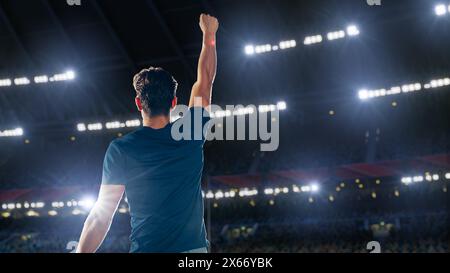 Portrait of Professional Male Athlete Happily Celebrating New Record for Winning Sport Championship. Determined Successful Sportsman Raising Arms Cheering for Gold Medal Victory. Shot on Large Stadium Stock Photo