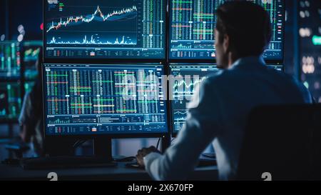 Financial Analysts and Day Traders Working on a Computers with Multi-Monitor Workstations with Real-Time Stocks, Commodities and Exchange Market Charts. Team of Brokers at Work in Agency. Stock Photo