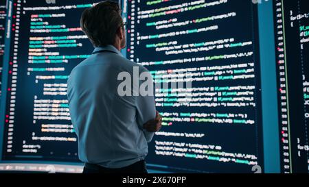 Innovative Computer Science Concept: Software Engineer Standing and Doing Information Technology Analysis on Big Wall Screen. Programmer Developing e-Commerce App. Stock Photo