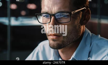 Portrait of Male Startup Digital Entrepreneur Working on Computer, Looking at Camera Line of Code Reflecting in Glasses. Developer Working on Innovative e-Commerce App using Big Data. Stock Photo