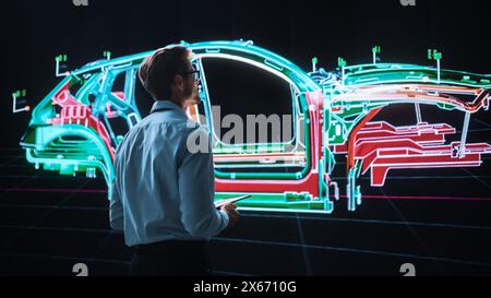 Innovative Green Energy Startup: Engineer Designing Electric Car Using Tablet Computer and Big Wall Screen to Analyse Prototype. Concept for Sustainable Environmnetally Friendly Zero Emissions Vehicle Stock Photo