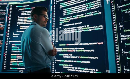 Innovative Startup Concept: Thoughtful Software Engineer Finding Solution, Planning Strategy, Standing and Doing Data Analysis on Big Wall Screen. Programmer Developing e-Commerce App. Stock Photo