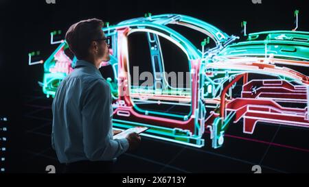 Innovative Green Energy Startup: Engineer Designing Electric Car Using Tablet Computer and Big Wall Screen to Analyse Prototype. Concept for Sustainable Environmnetally Friendly Carbon Neutral Vehicle Stock Photo