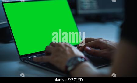 Close-up Focus on Person's Hands Typing on the Green Screen Chroma key Laptop Computer Keyboard. Software Engineer Create Innovative e-Commerce App. Program Development Stock Photo