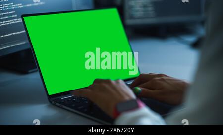 Close-up Focus on Person's Hands Typing on the Green Screen Chroma key Laptop Computer Keyboard. Software Engineer Create Innovative e-Commerce App. Program Development Stock Photo