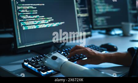 Focus on Hands: Programmer With Disability Using Prosthetic Arm to Work on Illuminated Computer Keyboard. Swift and Natural Use of Myoelectric Bionic Hand To Type Code for Software at Night. Stock Photo