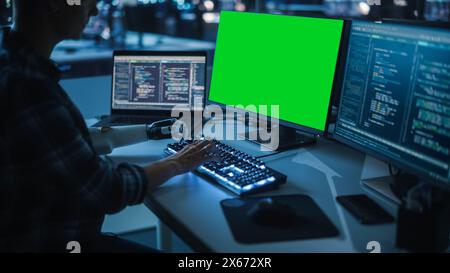 Night Office: Person with Disability Using Prosthetic Arm to Work on Green Screen Chroma Key Computer. Swift and Natural Use of Myoelectric Bionic Hand To Type Code for Software at Night. Stock Photo