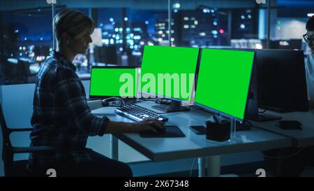 Night Office: Person with Disability Using Prosthetic Arm to Work on Green Screen Chroma Key Computer. Swift and Natural Use of Myoelectric Bionic Hand To Type Code for Software at Night. Stock Photo