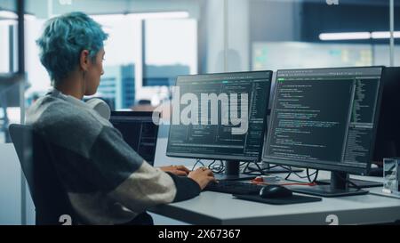 In Diverse Office: Female Programmer is Working on Desktop Computer, Screen Shows Coding Language User Interface. Digital Entrepreneur Creating Modern Software, e-Commerce App Design. Over Shoulder Stock Photo