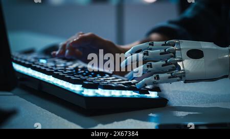 Close-up on Hands: Programmer With Disability Using Prosthetic Arm to Work on Backlit Computer Keyboard. Specialist Swift and Natural Use of Myoelectric Bionic Hand To Type for e-Commerce Software Stock Photo