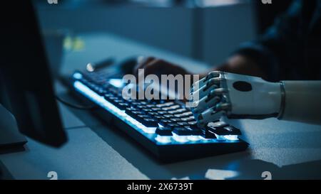 Close-up on Hands: Programmer With Disability Using Prosthetic Arm to Work on Computer Keyboard. Specialist Swift and Natural Use of Myoelectric Bionic Hand To Type Code for Software at Night Stock Photo