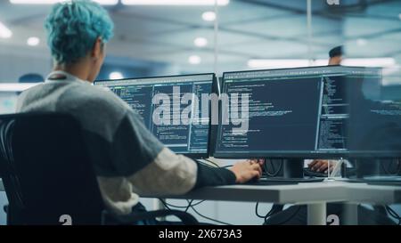 In Diverse Office: Female Programmer is Working on Desktop Computer, Screen Shows Coding Language User Interface. Digital Entrepreneur Creating Modern Software, e-Commerce App Design. Over Shoulder Stock Photo