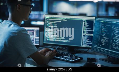 Night Office: Young Handsome Man in Working on Desktop Computer. Digital Entrepreneur Typing Code, Developing Modern Software, e-Commerce App Design, Developing of e-Business. Over Shoulder Stock Photo