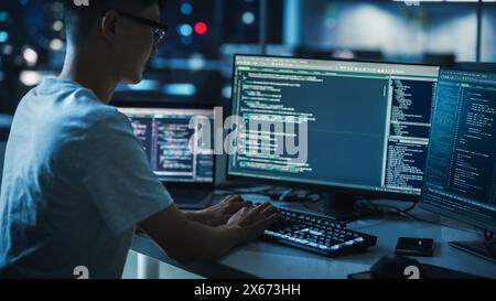 Night Office: Young Handsome Man in Working on Desktop Computer. Digital Entrepreneur Typing Code, Developing Modern Software, e-Commerce App Design, Developing of e-Business. Over Shoulder Stock Photo