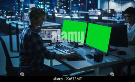 Night Office: Person with Disability Using Prosthetic Arm to Work on Green Screen Chroma Key Computer. Swift and Natural Use of Myoelectric Bionic Hand To Type Code for Software at Night. Stock Photo