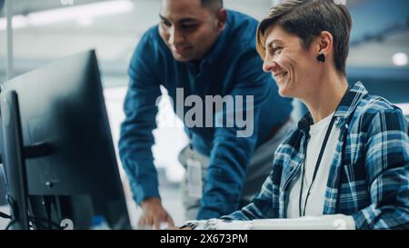 Teamwork In Diverse Office: Smiling Project Manager Talks with Happy Woman with Disability with Prosthetic Arm to Work on Computer. Professionals Create e-Commerce Software App. Stock Photo