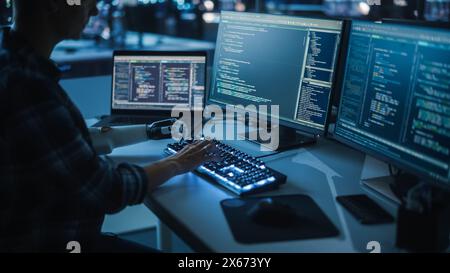 Night Office: Programmer With Disability Using Prosthetic Arm to Work on Computer Keyboard. Swift and Natural Use of Myoelectric Bionic Hand To Type Code for Software at Night. Stock Photo